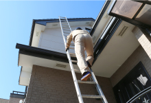 はしごをかけて屋根に上る現場調査スタッフ